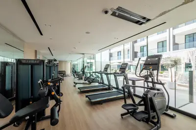 a gym with a row of treadms and cardio machines at New! Stylish Studio with Pool, Gym & Jacuzzi, JVC in Dubai