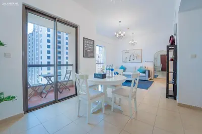 a dining room with a table and chairs and a living room at Gardenia Bahar Suites 1 Bedroom Apartment in JBR with 2 mins walk to the Beach in Dubai