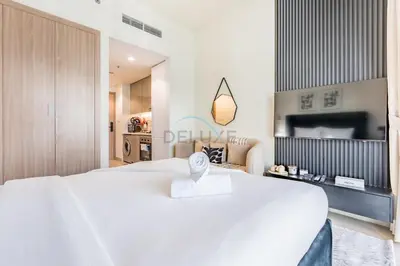 a bedroom with a large white bed and a tv at Furnished Studio Near Meydan Racecourse, Minutes to Downtown Dubai, Azizi Riviera 47, Al Merkadh by Deluxe Holiday Homes in Dubai