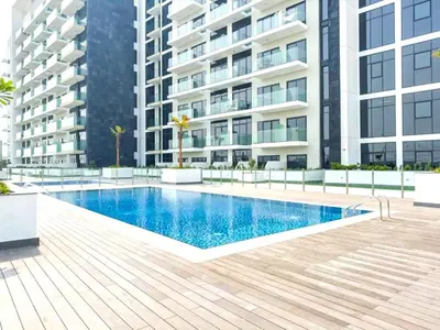 a swimming pool in front of a building at Furnished Studio Near Meydan Racecourse, Minutes to Downtown Dubai, Azizi Riviera 47, Al Merkadh by Deluxe Holiday Homes in Dubai