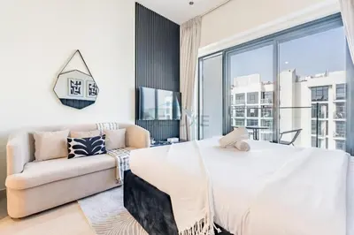 a bedroom with a white bed and a couch at Furnished Studio Near Meydan Racecourse, Minutes to Downtown Dubai, Azizi Riviera 47, Al Merkadh by Deluxe Holiday Homes in Dubai