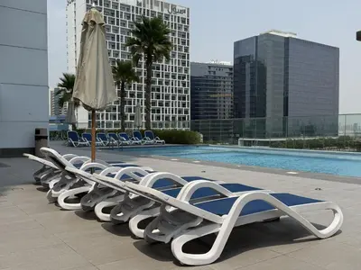 a row of lounge chairs and an umbrella next to a pool at Luxury Stay Dual View Furnished Swimming Pool Gym in Dubai