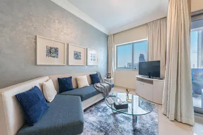 a living room with a couch and a tv at 2min to Dubai Mall - Pool, Gym, Sauna - Full Burj View in Dubai