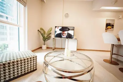 a living room with a glass table and a tv at Stylish and Charming 1BR in Urban Oasis by Missoni in Dubai