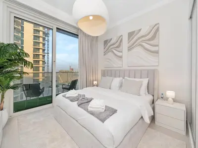 a white bedroom with a large bed and a large window at Palm and Marina Views in NEW Palace Beach Residence in Dubai