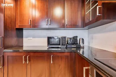 a kitchen with wooden cabinets and a microwave at bnbmehomes - 29 Boulevard Tower 1 in Dubai