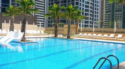 a large swimming pool with palm trees and chairs at Vacay Lettings - Marina Gate 2 in Sabkhah
