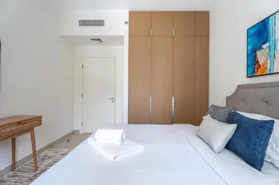 a bedroom with a white bed and a wooden cabinet at GuestReady - Stylish Stay with Dubai Skyline Views in Dubai