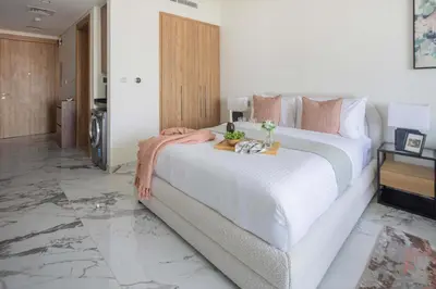 a bedroom with a large bed with white sheets and pink pillows at Frank Porter - Taraf 2 Residence in Dubai