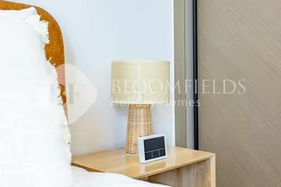 a lamp on a night stand next to a bed at Bloomfields Cozy 1BR Binghatti Nova in Dubai