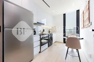 a kitchen with a stainless steel refrigerator and a table at Bloomfields Cozy 1BR Binghatti Nova in Dubai