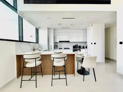 a kitchen with white cabinets and a counter with stools at Elevated 2br Elegance Dip Pool, Parking And Gym! in Dubai