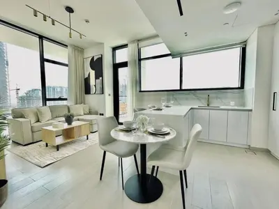 a kitchen and living room with a table and chairs at Elevated 2br Elegance Dip Pool, Parking And Gym! in Dubai