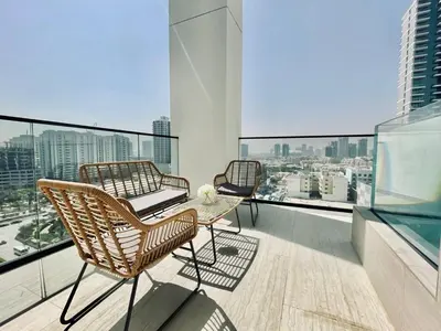 two chairs and a table on the balcony of a building at Elevated 2br Elegance Dip Pool, Parking And Gym! in Dubai