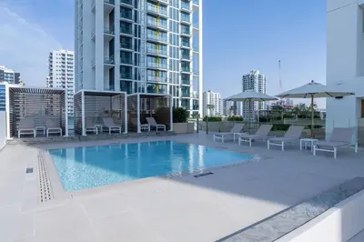 a swimming pool with chairs and umbrellas on a building at Elevated 2br Elegance Dip Pool, Parking And Gym! in Dubai