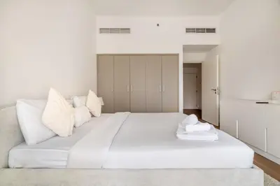 a white bedroom with a large white bed at New! 1BR with Balcony Views and Pool by Burj Khalifa in Dubai