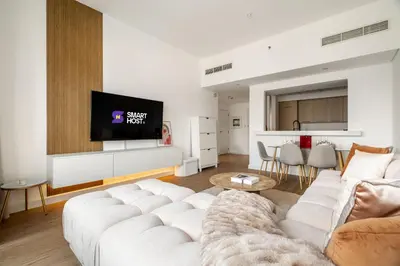 a living room with a white couch and a tv at New! 1BR with Balcony Views and Pool by Burj Khalifa in Dubai