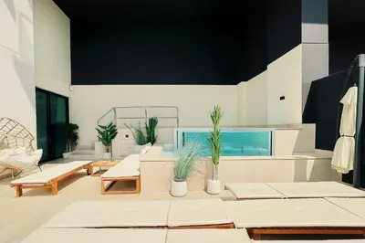 a living room with white furniture and potted plants at Sun Deck & Sleek Lap Pool Free Gym And Parking! in Dubai