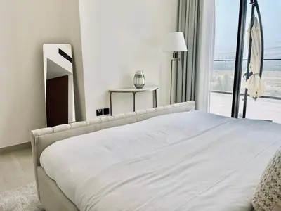 a white bed in a bedroom with a large window at Sun Deck & Sleek Lap Pool Free Gym And Parking! in Dubai