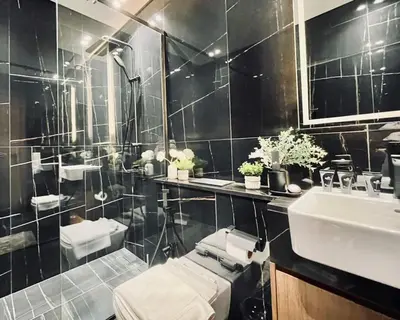 a black tiled bathroom with a sink and a mirror at Sun Deck & Sleek Lap Pool Free Gym And Parking! in Dubai