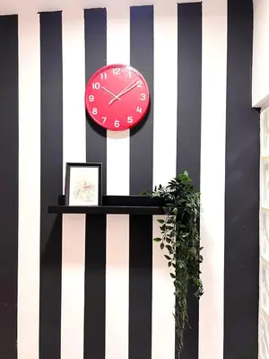 a red clock on a black and white striped wall at Duo Den Partiton Room In tecom Barsha Heights in Dubai