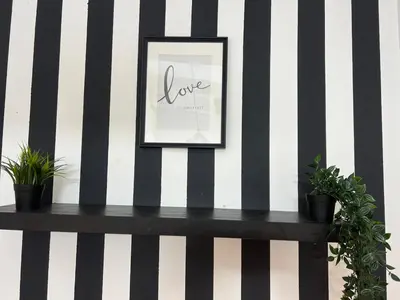 a black bench with potted plants on a wall at Eden Retreat Partition room For Couple In Barsha Heights in Dubai
