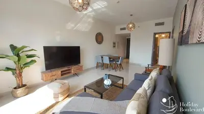a living room with a blue couch and a flat screen tv at Stylish 1br Brand New Prime Business Bay Stay in Dubai