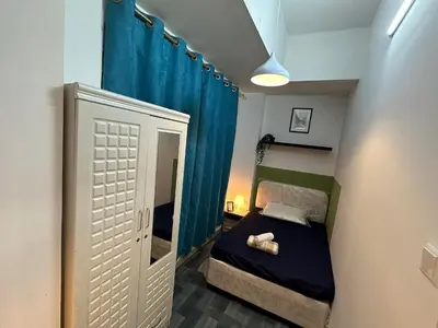 a small bedroom with a bed and a blue curtain at Enchanted Stay Partition Room in Barsha Heights in Tecom in Dubai