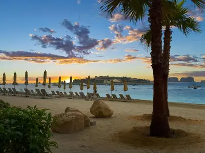a beach with umbrellas and chairs and a palm tree at Luxury Oasis | Private Beach & Infinity Pool in Dubai