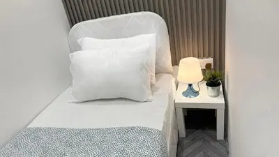 a bed with white pillows and a lamp on a table at Best Solo Room in Barsha heights Tecom in Dubai