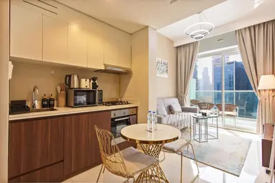 a kitchen and living room with a table and chairs at Comfy 1BR with Large Balcony - 15-min to Mall & Burj in Dubai