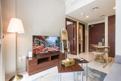 a living room with a tv and a couch at Comfy 1BR with Large Balcony - 15-min to Mall & Burj in Dubai