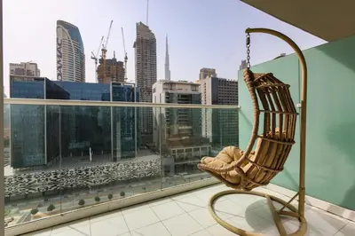 a chair on a balcony with a view of the city at Comfy 1BR with Large Balcony - 15-min to Mall & Burj in Dubai