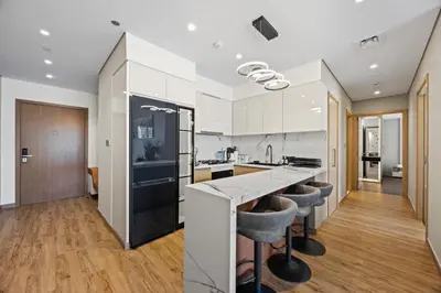 a kitchen with white cabinets and a counter with bar stools at 2BR Burj Khalifa Dubai Mall View in Dubai