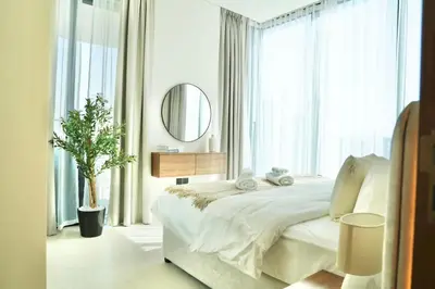 a white bedroom with a large bed and a mirror at Spacious 1BR Balcony Jacuzzi in Dubai