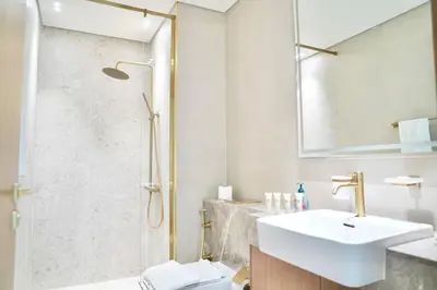 a white bathroom with a sink and a shower at Spacious 1BR Balcony Jacuzzi in Dubai