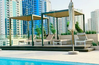 a pool with umbrellas and chairs next to a pool at Luxury Studio w Jacuzzi Balcony in Dubai