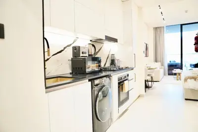 a white kitchen with a stove and a microwave at Luxury Studio w Jacuzzi Balcony in Dubai