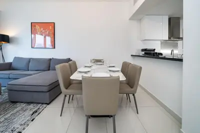 a living room with a table and a blue couch at Chic Waterfront 1 Bed with Panoramic Marina Views in Dubai
