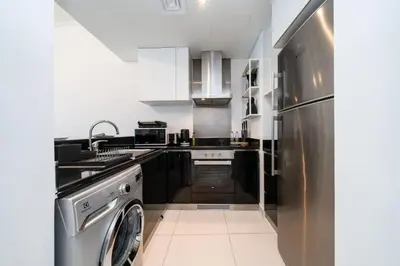 a kitchen with a stainless steel refrigerator and a dishwasher at Chic Waterfront 1 Bed with Panoramic Marina Views in Dubai