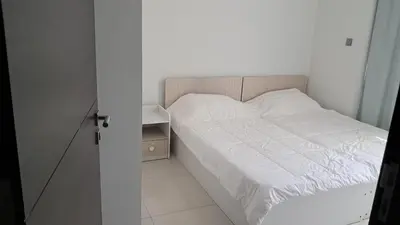 a bedroom with a white bed and a night stand at Damac hills 2 vardon cluster townhouse in Dubai