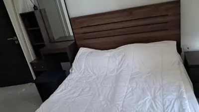 a bed with white sheets and a wooden headboard at Damac hills 2 vardon cluster townhouse in Dubai