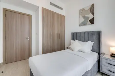 a bedroom with a white bed and a wooden door at GLOBALSTAY Elegant Meydan Apartments - Azizi Riviera 40 in Dubai