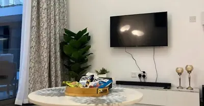 a living room with a table and a tv on a wall at Laya Heights Residence by Hogar in Dubai