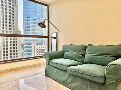 a green couch in a living room with a large window at Renovated 2bdr in Sadaf 7 JBR in Dubai