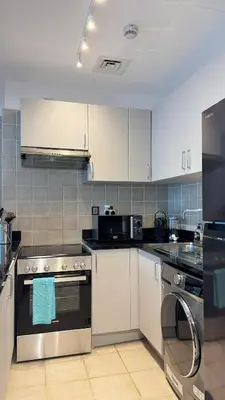 a kitchen with stainless steel appliances and white cabinets at DAYF-POLO Modern 1BR Escape Polo Residences Meydan in Dubai