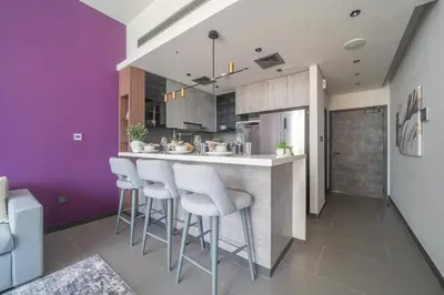 a kitchen with purple walls and a bar with stools at Frank Poretr - MBL Royal, Jumeirah Lakes Towers in Dubai