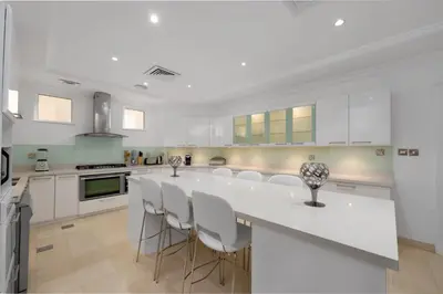 a white kitchen with a large white island with stools at Maison Privee - Ultra-Luxury Villa with Private Pool & Beach on Palm in Dubai