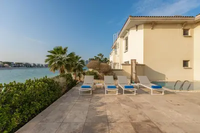 a group of chairs and a swimming pool next to a building at Maison Privee - Ultra-Luxury Villa with Private Pool & Beach on Palm in Dubai