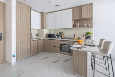 a kitchen with wooden cabinets and a counter with chairs at Frank Poretr - The Pinnacle, Dubai Hills in Dubai